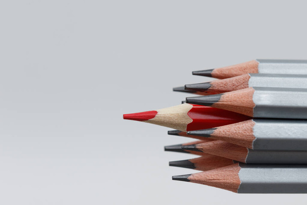 A red pencil standing out from the crowd of many identical gray brothers on a white background. Leadership, uniqueness, independence, initiative, strategy, dissent, think differently, business success concept - Foto, immagini