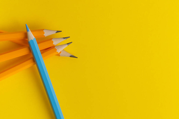 Um lápis azul no topo de um grupo de lápis amarelos. Conceito e ideia
 - Foto, Imagem