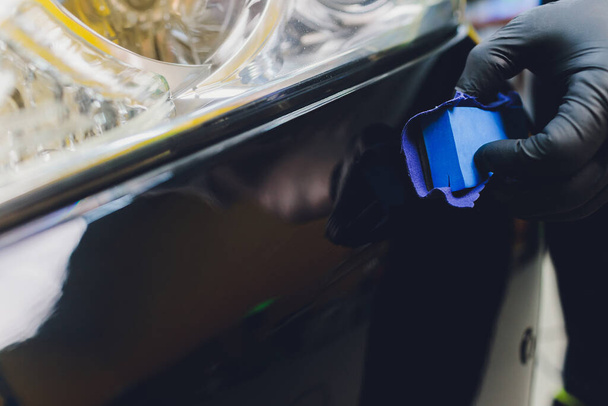 Car detailing - Man applies nano protective coating to the car. Selective focus. - Foto, Bild