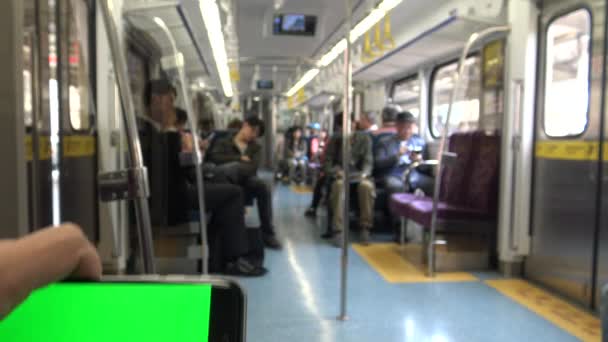 地下鉄で何かを見るためにスマートフォンを使用して電車の中で待っている男地下鉄では、彼は台湾ダンで彼の停留所駅に到着するのを待っている - 映像、動画