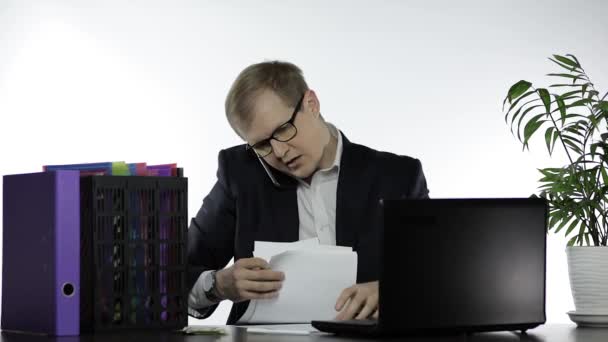 Virassa työskentelevä liikemies. Puhuu äänekkäästi puhelimessa lukiessaan lehtiä
 - Materiaali, video