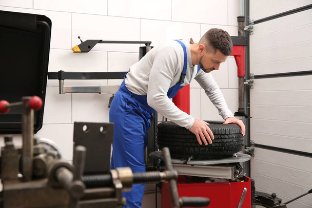 Mechanic working with tire fitting machine at car service - Foto, Imagem