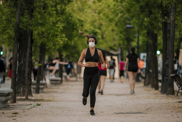 dívka dělá sporty s maskou na ulici během porodu coronavirus - Fotografie, Obrázek