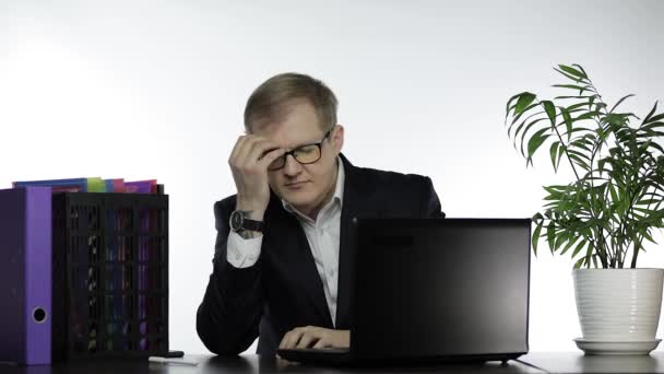 オフィスの疲れビジネスマンマネージャーは、ノートパソコンで作業頭痛を持っています - 映像、動画