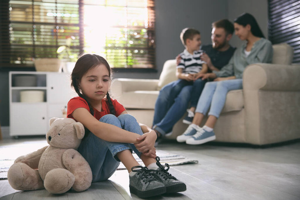 Unhappy little girl feeling jealous while parents spending time with her brother at home - Photo, Image