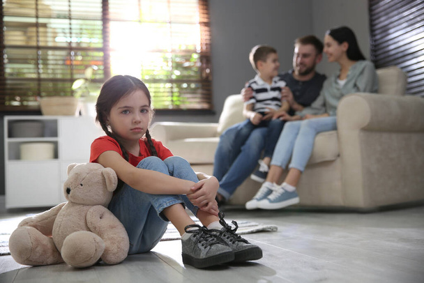 Unhappy little girl feeling jealous while parents spending time with her brother at home - Photo, Image