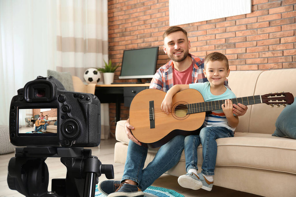 Father and son recording guitar lesson indoors. Teaching music - Photo, Image