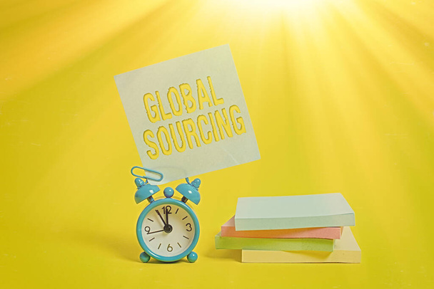Handwriting text writing Global Sourcing. Concept meaning practice of sourcing from the global market for goods Metal alarm clock blank sticky note stacked notepads colored background. - Photo, Image