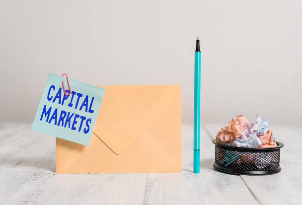Writing note showing Capital Markets. Business photo showcasing Allow businesses to raise funds by providing market security Envelope sticky note marker paper balls container wooden background. - Photo, Image