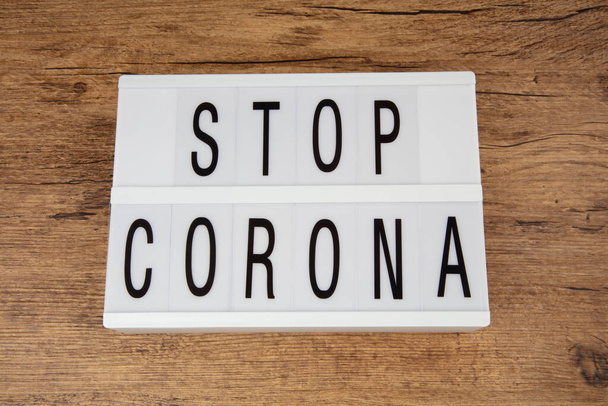 Concepto: Stop Corona en una caja de luz sobre fondo de madera
 - Foto, Imagen