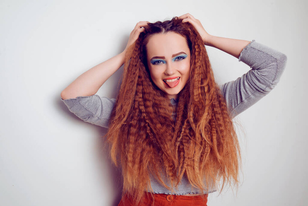 Dívka s kudrnaté objemné vlasy, model s účesem ve stylu 80. let. 90. léta s jasně modrým make-upem. Péče o vlasy, brunetka zrzavá dívka s dlouhými vlasy, kadeře, vlnité vlasy - Fotografie, Obrázek