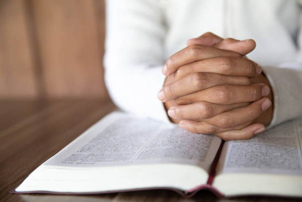 Bir kadın oturuyor ve İncil okuyor ve Tanrı 'nın kudretine olan inancıyla Hristiyanlık ve İsa' ya dua ederek Tanrı 'nın kutsal gücüne olan inancı için dua ediyor. - Fotoğraf, Görsel