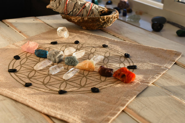 Een close-up afbeelding van chakra balancerende kristallen op een houten tafel met het gloeiende avondzonlicht dat de kristallen verwarmt.  - Foto, afbeelding