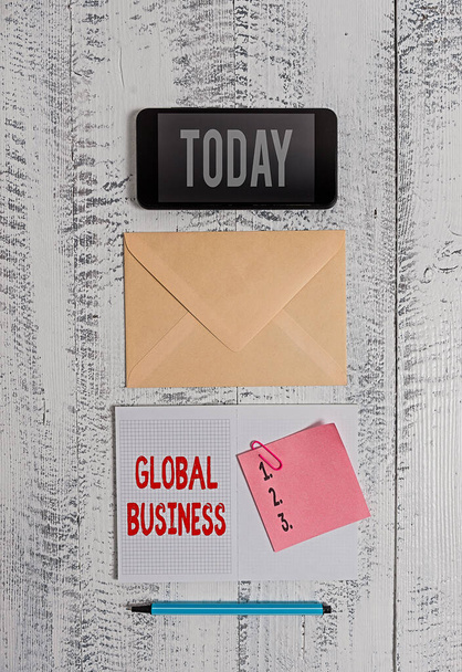 Word writing text Global Business. Business concept for Trade and business system a company doing across the world Envelop smartphone notepad note clip marker old wooden vintage background. - Photo, Image