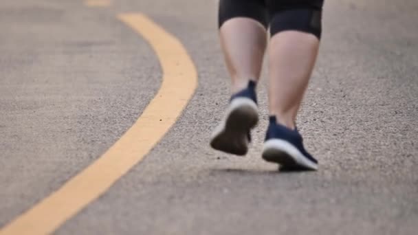 Feche os pés de mulher correndo na estrada no parque. Uma mulher a correr à noite. Saúde e fitness. Movimento lento
 - Filmagem, Vídeo