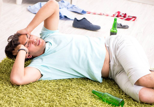 Молодой пьяный красивый мужчина после вечеринки дома - Фото, изображение