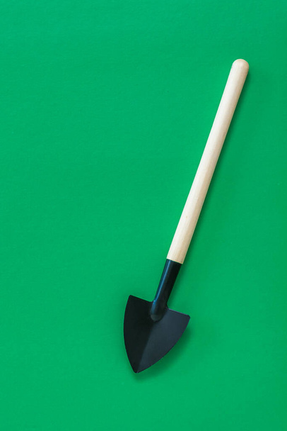 Классическая лопата с деревянной ручкой на зеленом фоне
. - Фото, изображение