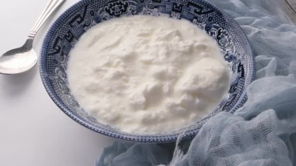 close up of fresh yogurt in a bowl on color background  - Πλάνα, βίντεο