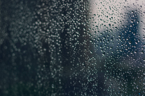 Borroso y el enfoque de la gota de lluvia en la ventana de cristal en la temporada de monzones con fondo borroso edificio para el concepto abstracto y de fondo. - Foto, imagen