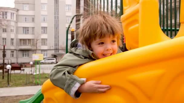 Podekscytowany chłopiec bawiący się na placu zabaw - Materiał filmowy, wideo