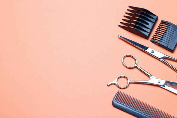 Herramientas de peluquería, tijeras y peine sobre un fondo naranja, una réplica del espacio
 - Foto, imagen