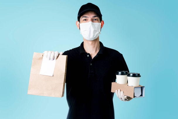 Deliveryman holding paper bag with food and coffee cups. Concept deliveries, groceries and food supplies. Cyan background. - Photo, Image
