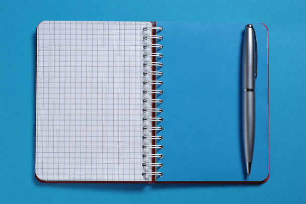 Cuaderno y pluma sobre fondo azul primer plano, vista superior
 - Foto, imagen