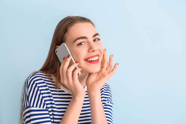 Όμορφη νεαρή γυναίκα μιλάει από το τηλέφωνο στο φόντο χρώμα - Φωτογραφία, εικόνα