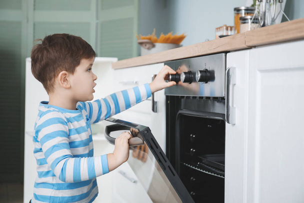 Kleine jongen spelen met elektrische oven thuis - Foto, afbeelding