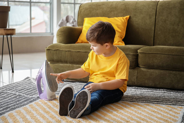 Маленький мальчик играет с утюгом дома
 - Фото, изображение