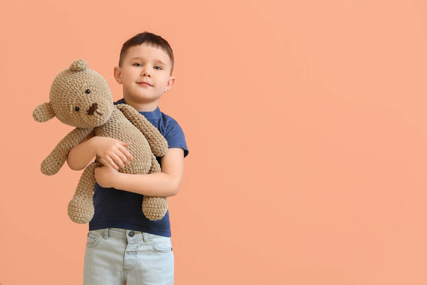 Cute little boy with toy bear on color background - Фото, изображение