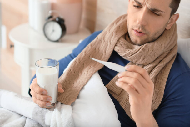 Jeune homme malade de la grippe boire du lait au lit
 - Photo, image