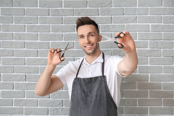 Male hairdresser on brick grey background - Photo, Image