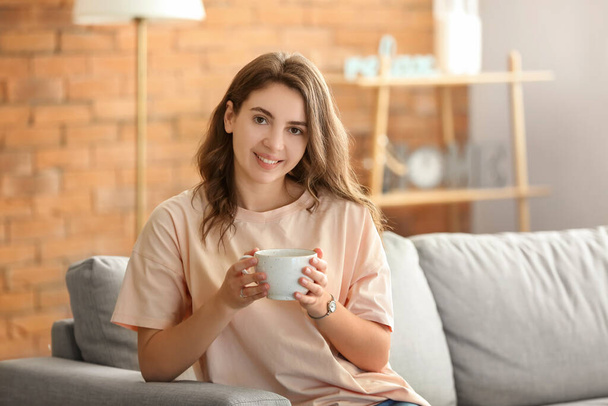 Красива молода дівчина п'є каву вдома
 - Фото, зображення