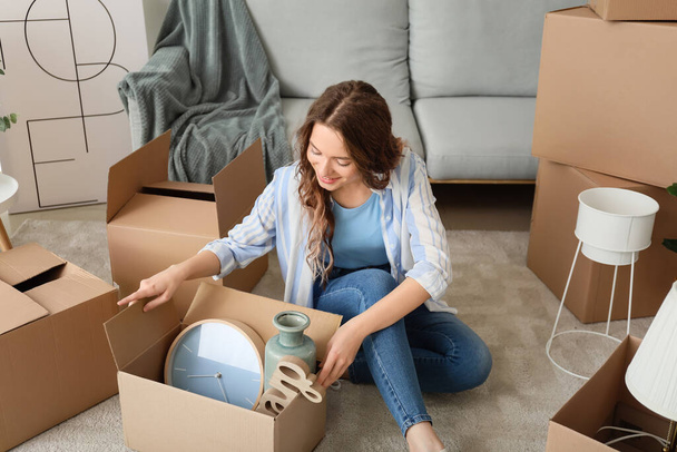 Молода жінка розпаковує рухомі коробки в своєму новому будинку
 - Фото, зображення
