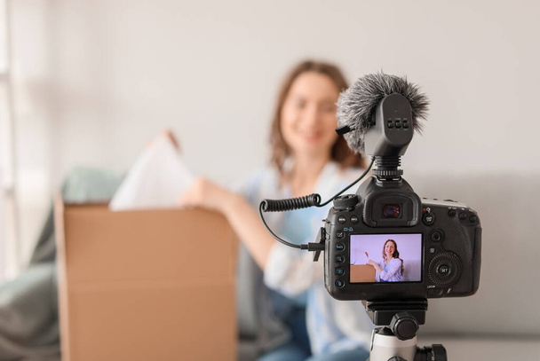 Young female blogger recording video while unpacking parcel at home - Photo, Image