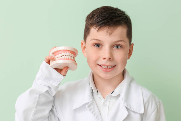 Kleiner Zahnarzt mit Kiefermodell auf farbigem Hintergrund - Foto, Bild