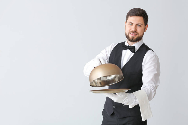 Cameriere maschio con vassoio e cloche su sfondo grigio
 - Foto, immagini