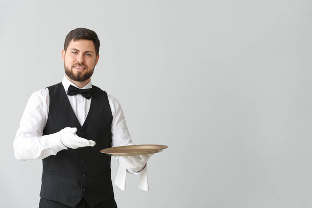 Mężczyzna kelner z pustą tacą na szarym tle - Zdjęcie, obraz