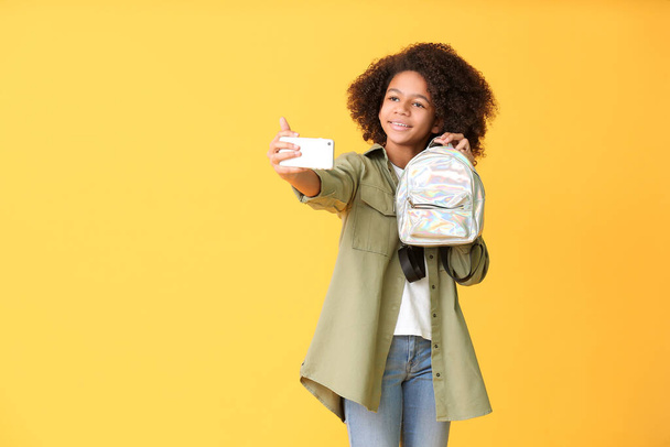 African-American teenage fashion blogger with mobile phone on color background - 写真・画像