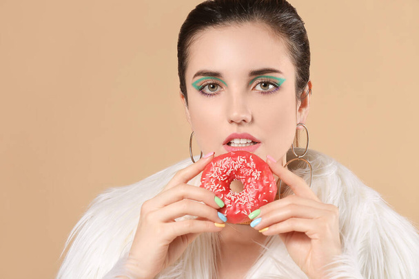 Young woman with beautiful manicure and donut on color background - Foto, Bild