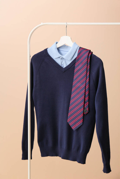 Stylish school uniform hanging on rack against color background - Photo, Image