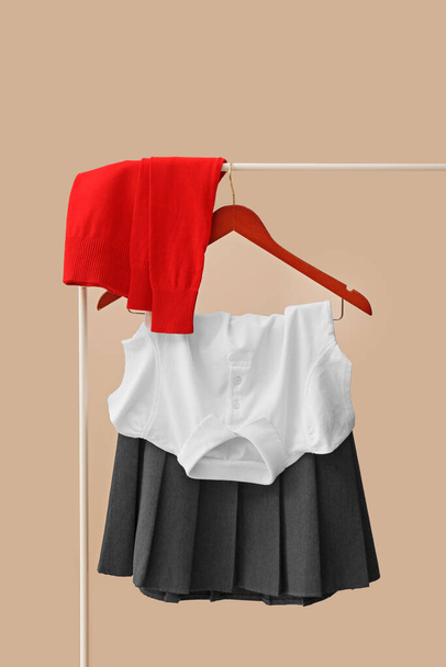 Elegante uniforme escolar colgado en el bastidor contra el fondo de color
 - Foto, imagen