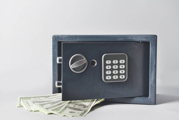Caja fuerte moderna con billetes en dólares sobre fondo claro
 - Foto, Imagen