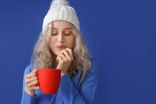 Beautiful young woman with cup of hot chocolate on color background - Zdjęcie, obraz