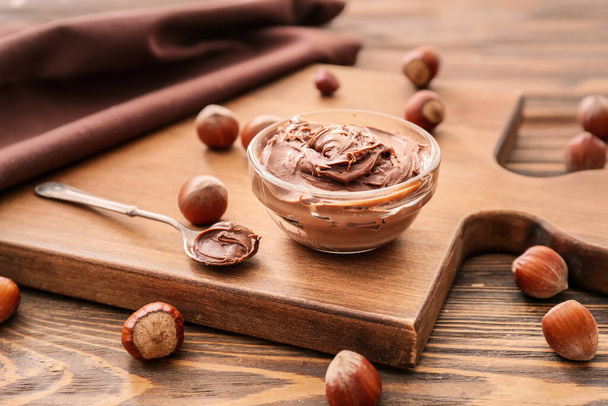 Bowl with tasty chocolate paste and hazelnuts on table - Zdjęcie, obraz