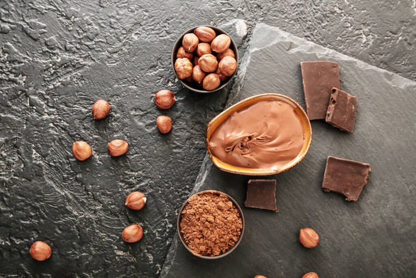 Bowls with tasty chocolate paste and hazelnuts on dark background - Photo, Image