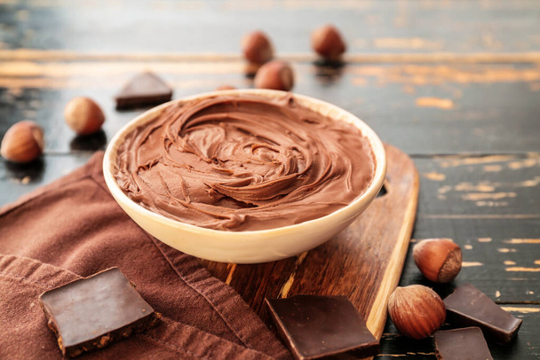 Bowl maukasta suklaatahnaa ja hasselpähkinöitä pöydällä
 - Valokuva, kuva