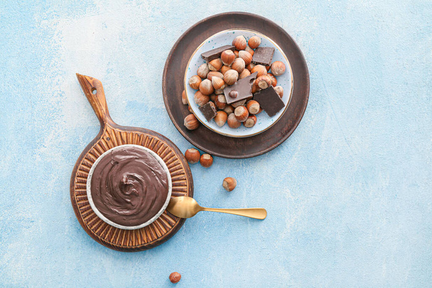 Placas com pasta de chocolate saborosa e avelãs no fundo de cor
 - Foto, Imagem