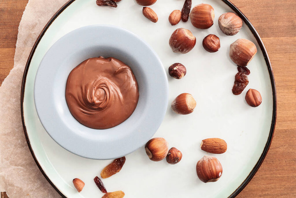 Levy maukas suklaa tahna ja pähkinät pöydällä
 - Valokuva, kuva